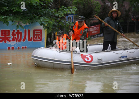 Chinese rescuers evacuate local residents by inflatable life boat from flooded areas after heavy rain in Lutang village of Xiushui county, east China' Stock Photo