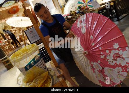 The seventh generation successor of Luzhou's oil paper umbrella Yu Wanlun makes an oil paper umbrella at his studio in Hangzhou city, east China's Zhe Stock Photo