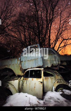 Old abandoned cars stacked on atop the other in 'car graveyard' at night, Bastnas, Sweden April Stock Photo
