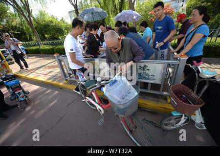 An elderly Chinese man prepares to leave after filling his bucket to take water from a roadside drinking fountain in Ji'nan city, east China's Shandon Stock Photo