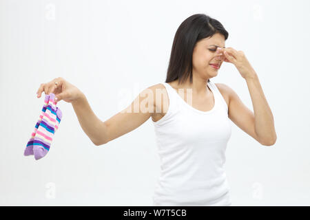 Young woman holding dirty socks Stock Photo