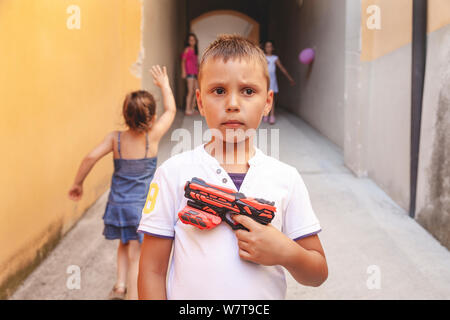 portrait of little boy with a water gun while playing outdoors Stock Photo