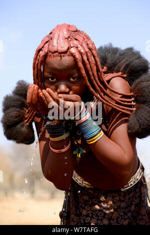 Young Himba woman drinking water from a fountain. Kaokoland, Namibia, September 2013.