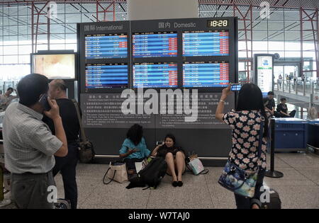 --FILE--Passengers look at a display of departure information showing domestic and international flights at Beijing Capital International Airport in B Stock Photo