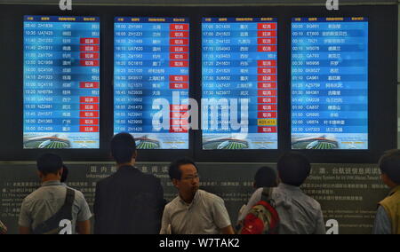 --FILE--Passengers look at a display of departure information showing domestic and international flights at Beijing Capital International Airport in B Stock Photo