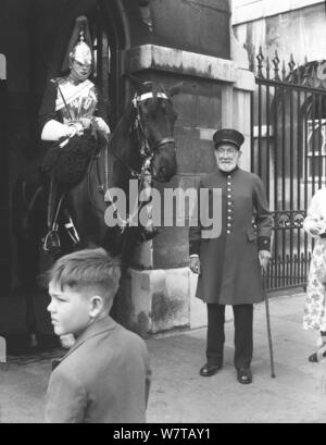 1956, historical, a chelsea pensioner in his military uniform and the letters RH on his hat standing outside a sentry box of the Queen's Cavalry at Horse Guards, Westminster, London, England, UK. A Chelsea Pensioner is an army veteran who lives at the Royal Hospital Chelsea, a retirement and nursiing home for former military personnel. Stock Photo