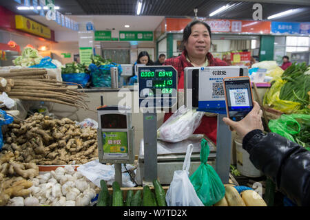 --FILE--A customer uses her smartphone to scan a QR code offered by a vendor to pay by Chinese online payment service Alipay of Alibaba's Ant Financia Stock Photo