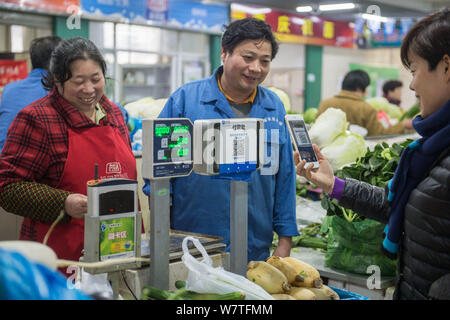 --FILE--A customer uses her smartphone to scan a QR code offered by a vendor to pay by Chinese online payment service Alipay of Alibaba's Ant Financia Stock Photo