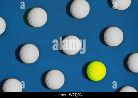 Creative composition made with yellow tennis ball and white balls on blue background. Sport tennis pattern. Diversity and difference concept. Flat lay Stock Photo