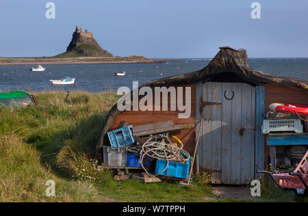 Fisherman's shed made from old upturned boat with Lindisfarne Castle behind, Lindisfarne Island, Northumberland , UK, Octobber 2013. Stock Photo