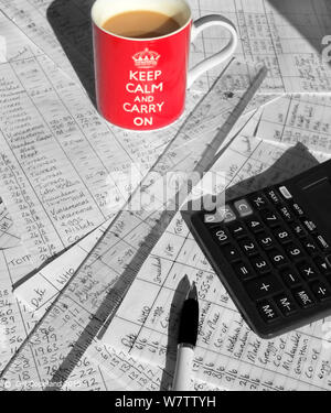 A red coffee mug ith the words keep calm and carry on written on it on top of business accounts paper work with a lot of hand written math calculation Stock Photo