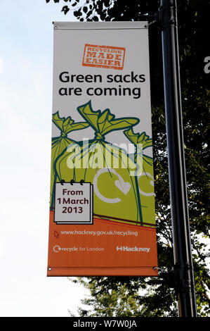 Banner saying 'Green sacks are coming' hanging from lamppost to encourage local residents to recycle their waste. The London Borough of Hackneys operates a mixed or commingled system of recycling, Hackney, London, UK,  August 2013. Stock Photo