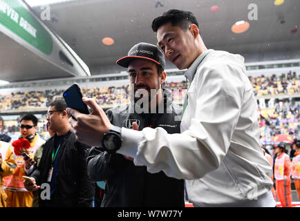 Spanish F1 driver Fernando Alonso of McLaren, left, takes selfies with retired Chinese table tennis player Wang Liqin ahead of the 2017 Formula One Ch Stock Photo