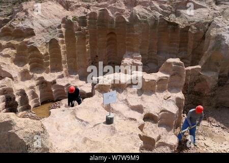 Chinese workers excavate the 600-year-old millstone pits spread out within a 7,000-square-meter area to obtain millstones used to grind rice and beans Stock Photo