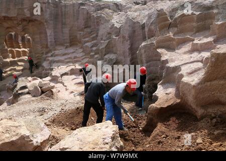 Chinese workers excavate the 600-year-old millstone pits spread out within a 7,000-square-meter area to obtain millstones used to grind rice and beans Stock Photo