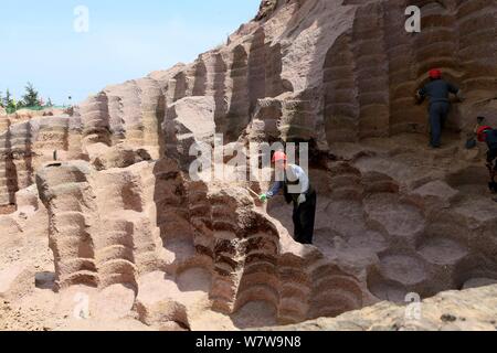 Chinese workers excavate the 600-year-old millstone pits spread out within a 7,000-square-meter area to obtain millstones used to grind rice and beans Stock Photo