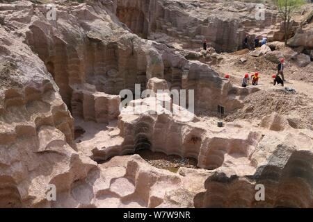 Chinese workers excavate the 600-year-old millstone pits spread out within a 7,000-square-meter area to obtain millstones used to grind rice and beans Stock Photo