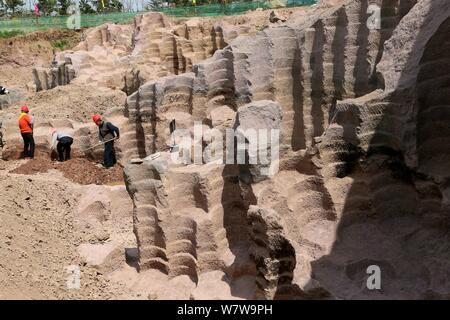 Chinese workers excavate the 600-year-old millstone pits spread out within a 7,000-square-meter area to obtain millstones used to grind rice and beans Stock Photo