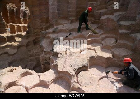 Chinese workers excavate the 600-year-old millstone pits spread out within a 7,000-square-meter area to obtain millstones used to grind rice and beans Stock Photo