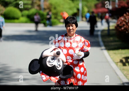 Elderly Chinese woman Yin Pizhi in her 70s, who plays Minnie Mouse to raise money for the treatment of her daughter-in-law, holds her rewards after po Stock Photo