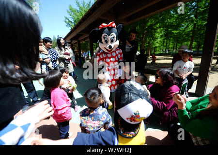 Elderly Chinese woman Yin Pizhi in her 70s, who plays Minnie Mouse to raise money for the treatment of her daughter-in-law, plays with children at a p Stock Photo