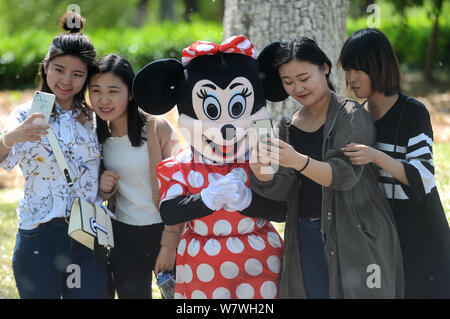 Elderly Chinese woman Yin Pizhi in her 70s, who plays Minnie Mouse to raise money for the treatment of her daughter-in-law, poses for group photos wit Stock Photo