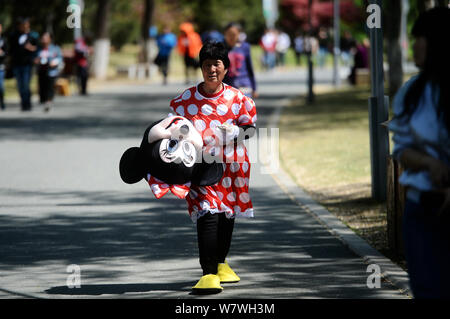 Elderly Chinese woman Yin Pizhi in her 70s, who plays Minnie Mouse to raise money for the treatment of her daughter-in-law, holds her rewards after po Stock Photo
