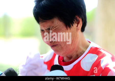 Elderly Chinese woman Yin Pizhi in her 70s, who plays Minnie Mouse to raise money for the treatment of her daughter-in-law, weeps at a park in Ji'nan Stock Photo