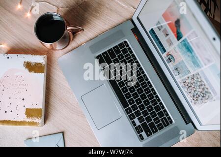 Closeup shot of a gray laptop, a journal and a cup of coffee on a table Stock Photo