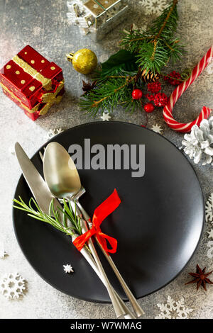 Christmas background. Christmas decoration table. Festive black plate and cutlery with Christmas decor on retro festive table. Stock Photo