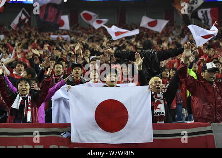 Football fans wave Japanese national flags and shout slogans to show support for Japan's Urawa Red Diamonds in their Group F match against China's Sha Stock Photo