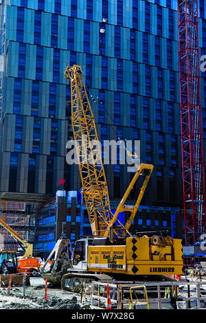 A crane with a clamshell bucket sits parked at a construction site in Kendall Square, Cambridge, Massachusetts. Stock Photo