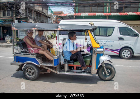 SAMUT PRAKAN, THAILAND, JUN 03 2019, Young couple rides in a traditional tricycle. Tuk tuk on city street. Stock Photo