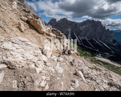 Trekkers enjoy the rugged mountain scenery en-route to the Rotwand hut mountain refuge in the Rosengarten area of the Italian Dolomites the Alto Adige Stock Photo