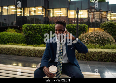 African American businessman holding mobile phone wearing blue suit Stock Photo