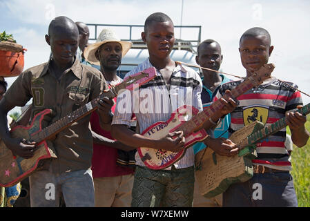 Men in village playing on home made four string guitars on road to Katanga, Democratic Republic of Congo, March 2012. Stock Photo