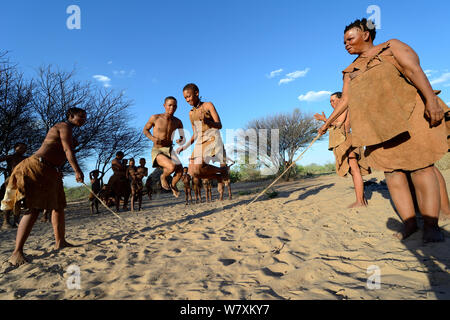 Naro San Bushmen family, women and children playing with skipping rope, Kalahari, Ghanzi region, Botswana, Africa. Dry season, October 2014. Stock Photo