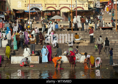 Busy riverside scene with women washing clothes on the side of the Ganges, Varanasi, Ghats, Uttar Pradesh, India, February 2012. Stock Photo