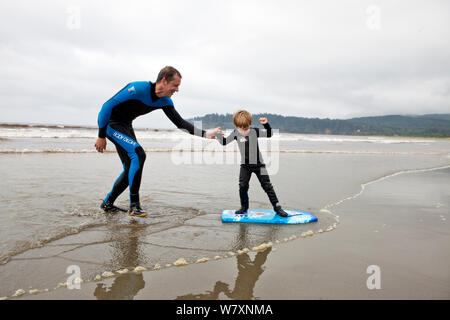 Nate Harrison teaching his son Gabriel how to surf, Hobuck Beach, Makah Reservation, Washington, USA, August 2014. Model Released. Model released. Stock Photo