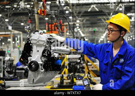 A Chinese worker assembles cars on the assembly line at an auto plant ...