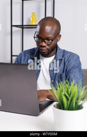 Freelancer african man working on laptop online, while making new project at home Stock Photo