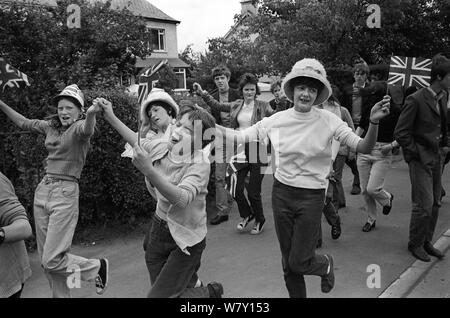 Belfast Orange Day Parade, teen girls dancing through the street with Union Jack flags.July 1970 UK. Northern Ireland. 1970s HOMER SYKES Stock Photo