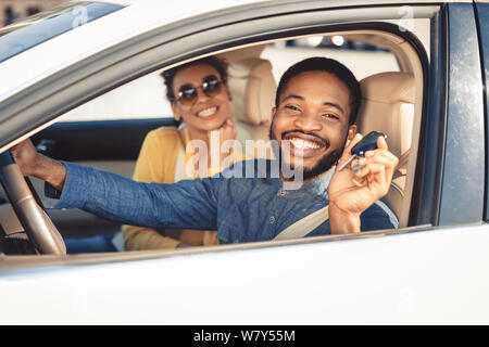 Visiting car dealership. Afro couple showing car key Stock Photo