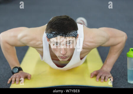 Athlete with a beautiful body doing push-ups exercise on the floor at the gym Stock Photo