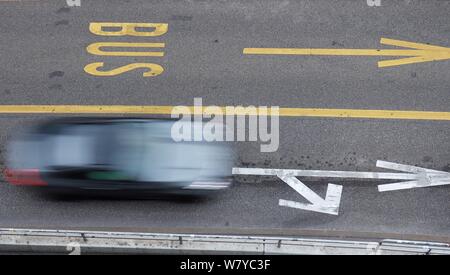 Blurred black car in motion driving next to bus lane. Stock Photo