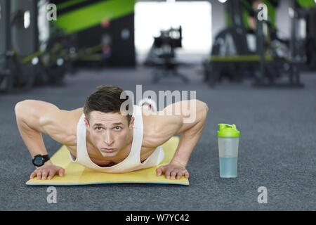 Front view of young athlete man portrait doing push up exercise at the gym Stock Photo