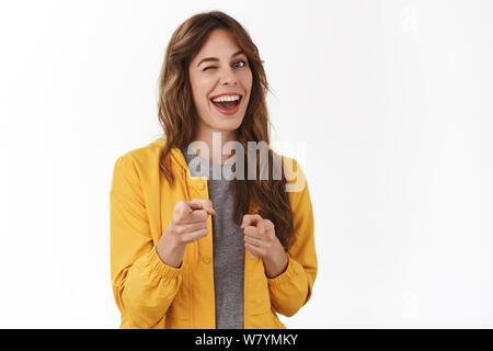 Gotcha. Hey wanna be friends. Cheeky confident relaxed young party girl smiling broadly winking approval pointing camera finger pistols you nice work Stock Photo