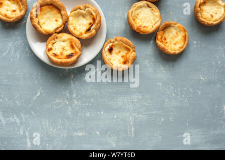 Portuguese custard tarts Pastel de Nata. Traditional Portuguese pasties for breakfast on blue background, top view, copy space. Stock Photo