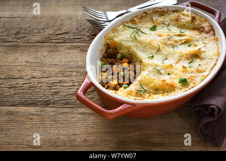 Shepherd's Pie with ground beef, potato and cheese on wooden background, top view, copy space. Traditional homemade casserole - Shepherds Pie. Stock Photo