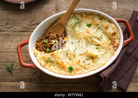 Shepherd's Pie with ground beef, potato and cheese on wooden background, top view, copy space. Traditional homemade casserole - Shepherds Pie. Stock Photo